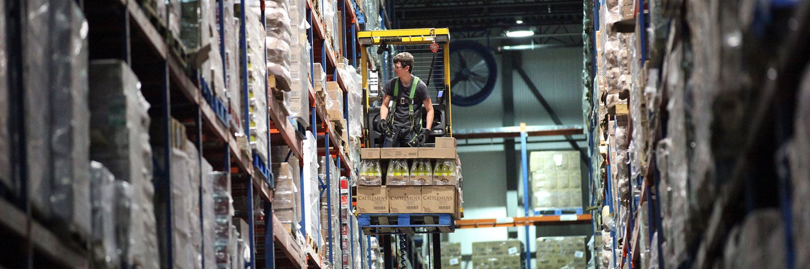 Close up of a Dot Foods warehouse employee on a raised forklift picking product