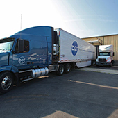 Driver side facing Dot Foods blue and white Volvo truck being loaded at a dock