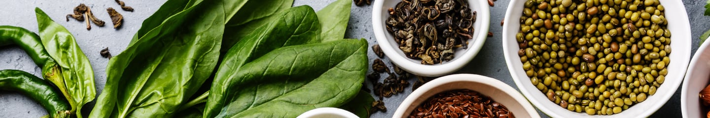 Fresh spinach leaves and various kitchen spices in white bowls