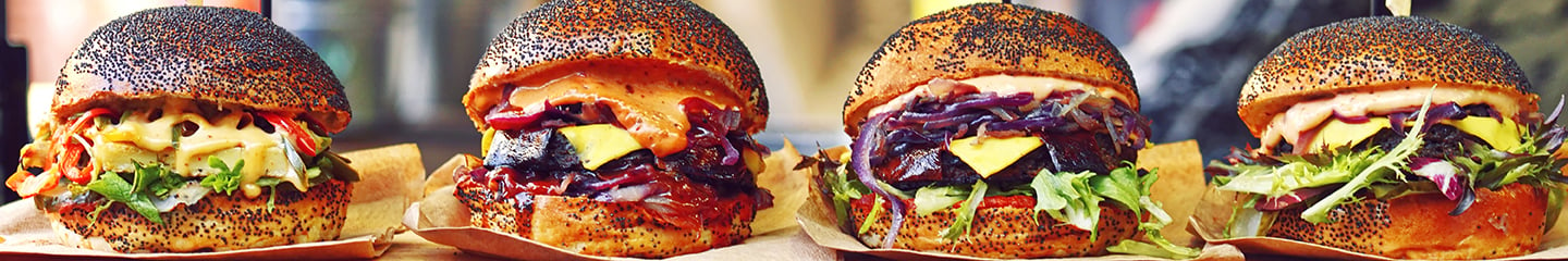 Four plant-based meat sandwiches on a black sesame bun