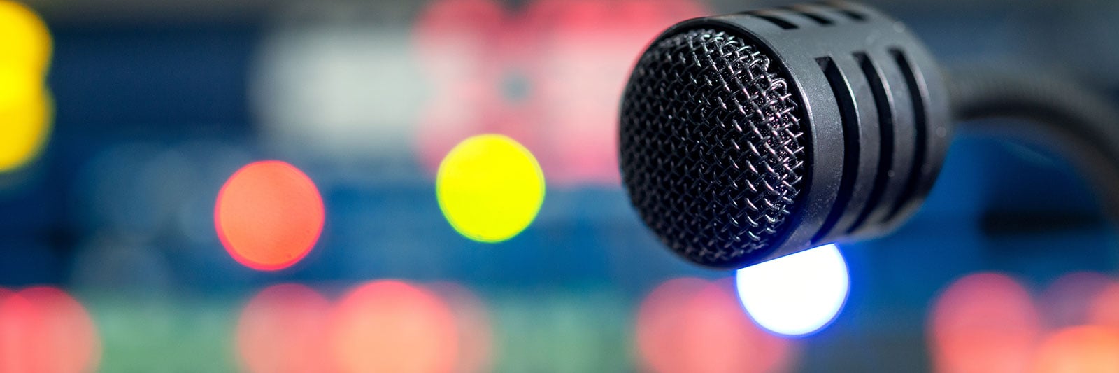 Close up of a microphone with multicolored lights out of focus in the background