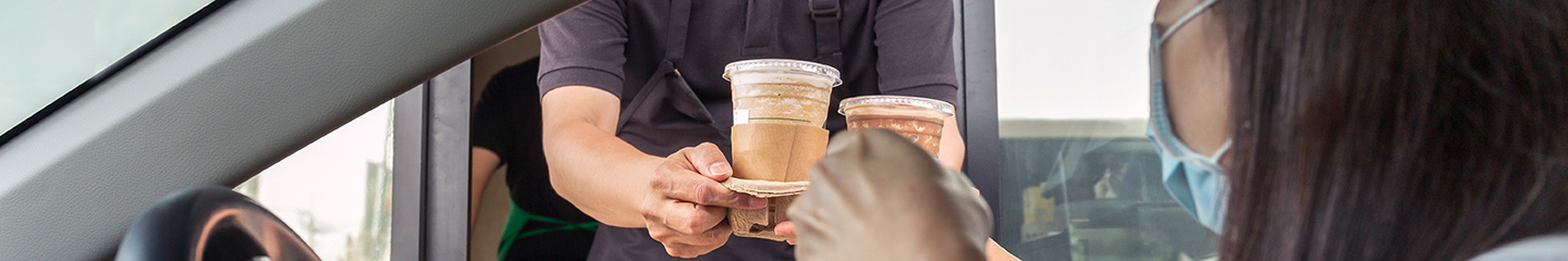 Female going through a drive-thru window to get two coffee drinks