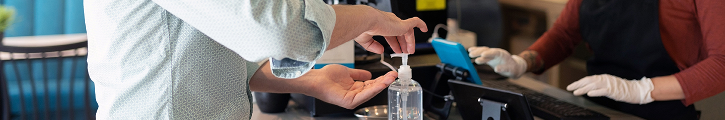 Man using hand sanitizer while getting checked out by a female restaurant employee