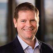 Headshot of man smiling in professional collared shirt and jacket