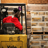 Male warehouse employee backing up a forklift