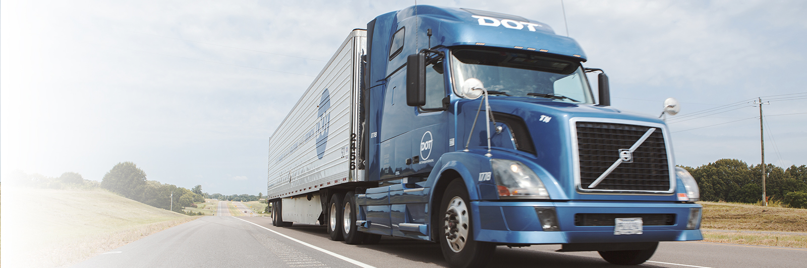 Picture of blue Dot truck with white trailer on road